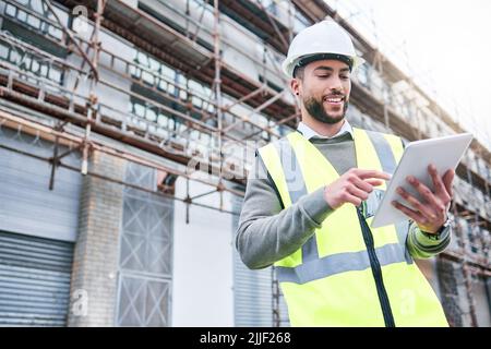 Success is a personal standard. a handsome male construction worker using a tablet while standing outside. Stock Photo