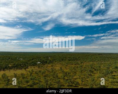 Drone aerial over homes separated by vast bushland under a cloudy blue sky. Stock Photo