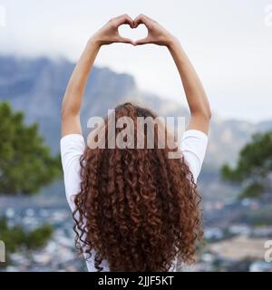 Loving nature. Rearview shot of an unrecognizable young woman out for an early morning hike in the mountains. Stock Photo