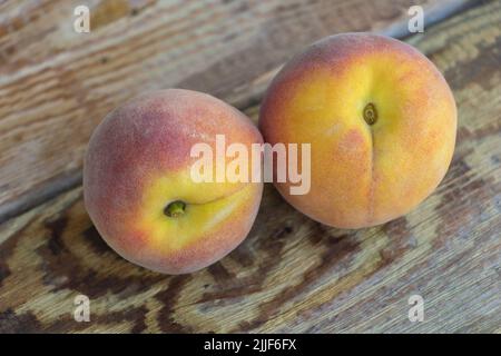 Two fresh peaches on wooden background close up. Stock Photo