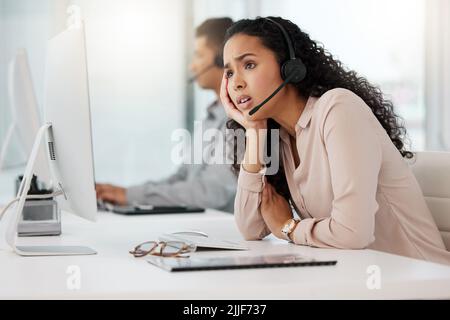 Stuck in a rut. a young call centre agent looking stressed out while working on a computer in an office. Stock Photo