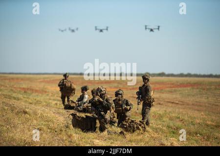 U.S. Marines with 3d Battalion, 7th Marine Regiment, Ground Combat Element, Marine Rotational Force-Darwin 22, establish defensive positions as MV-22 Ospreys approach for landing during an airfield seizure event as part of exercise Koolendong 22 at Royal Australian Air Force Base Curtin, WA, Australia, July 18, 2022. Exercise Koolendong 22 is a combined and joint force exercise focused on expeditionary advanced base operations conducted by U.S. Marines, U.S. Soldiers, U.S. Airmen, and Australian Defence Force personnel. (U.S. Marine Corps photo by Cpl. Cedar Barnes) Stock Photo