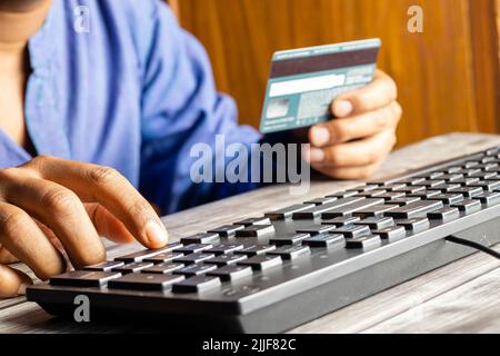 Selective focus on an Indian male hand using credit or debit card in front of computer Stock Photo