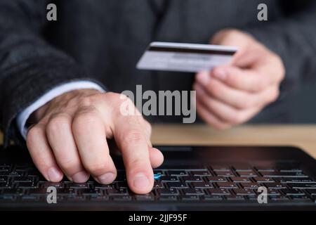 man hands card typing laptop online banking login Stock Photo