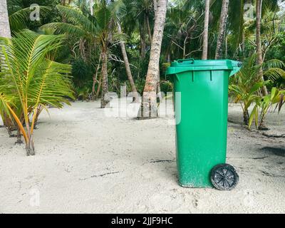 Green garbage bin on a tropical beach Stock Photo