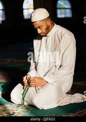 We are to pray in times of prosperity. a young muslim male praying in a mosque. Stock Photo