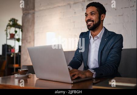 Happy young businessman having coffee and doing his work in cafe. Stock Photo
