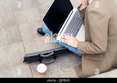 young woman working with laptop computer outdoors Stock Photo