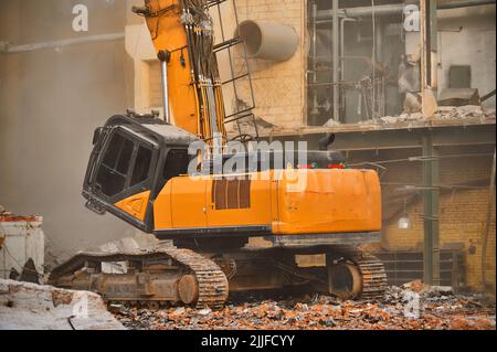 Hydraulic excavator with caterpillars demolishes old factory Stock Photo