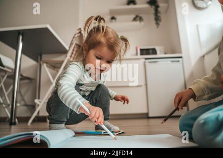 Two children playing on the kitchen floor Stock Photo