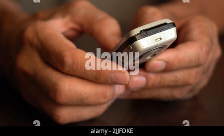 A button phone in the wrinkled hands of an elderly person Stock Photo