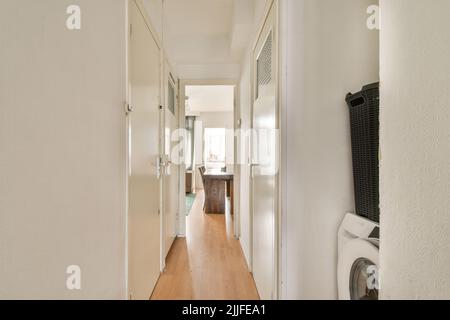 Interior of modern flat in minimal style with narrow empty corridor illuminated by lamps Stock Photo