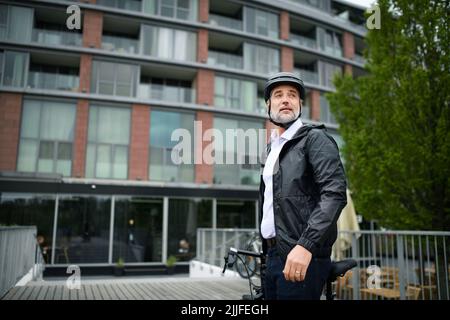 Businessman commuter on the way to work, pushing bike, sustainable lifestyle concept. Stock Photo
