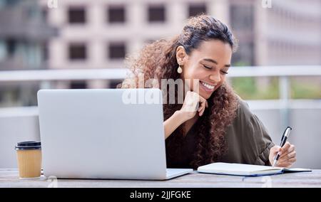 Refreshing her mind. a young businesswoman using a laptop and notebook at work. Stock Photo