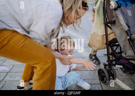 Young mother comforting crying little girl outdoor on walk. Concept of disobedient child Stock Photo