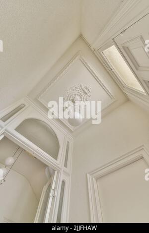 From below classic plaster floral ornament of medallion decorating ceiling above elegant chandelier at home Stock Photo