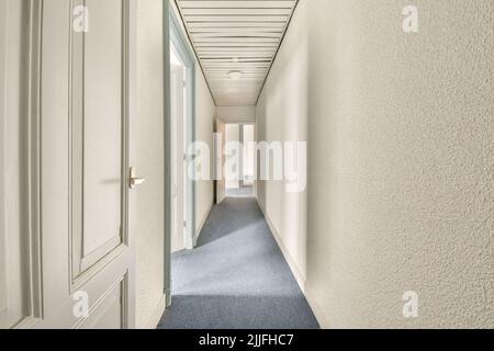 Interior of modern flat in minimal style with narrow empty corridor illuminated by lamps Stock Photo
