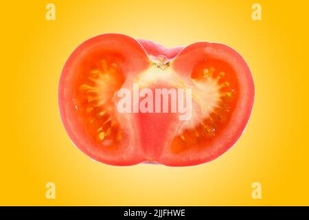 Close up of a half sliced fresh, organic red tomato on a vibrant orange gradient background. Stock Photo