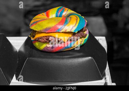 Unicorn Burger Hampshire minced steak rainbow bagel glitter for sale on food stall at event in Poole, Dorset UK in July - selective colour colouring Stock Photo