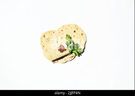 Flat lay homemade chapati, pita bread, flatbread with parsley, isolated over white background. Still life. Copy space Stock Photo