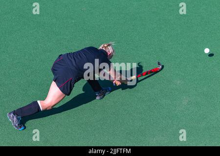 Hockey game girl player pushes pass the ball on astro turf overhead action photo. Stock Photo