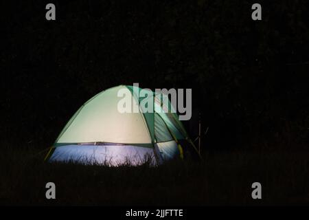 The glow from a camping tent at night Stock Photo