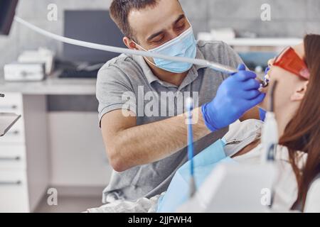 confident dentist is using a drill machine in modern light stamotology cabinet Stock Photo
