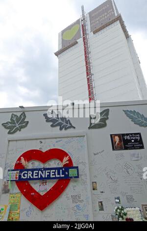 Grenfell Tower fire tragedy block, shown behind the memorial wall for the 72 victims. Grenfell United, Forever, after the cladding fire in 2017 Stock Photo