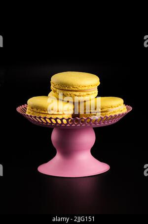 Yellow Macarons on a black background French pasta. Stack of yellow macaron with isolated on dark, black background. Macaroons. Stock Photo