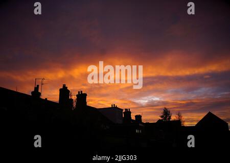 Stunning sunset over dark house rooftops and chimneys Stock Photo