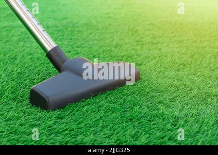 Selective focus of a vacuum cleaner on a sheet of artificial turf. Lawn care and maintenance. Easy to clean artificial greenery roll Stock Photo