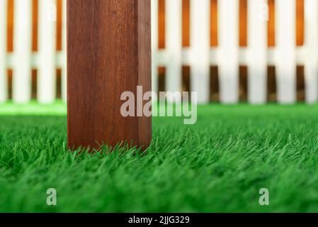 Selective focus on the wooden leg of a garden table on artificial turf. Realism of the leaves of an artificial lawn Stock Photo