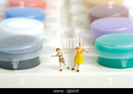 Miniature people toy figure photography. Coloring concept. Kids playing watercolor bottle, isolated on white background. Image photo Stock Photo