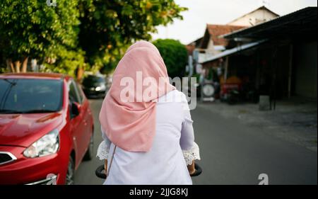 Rear view young asian muslim woman cycling in the street Stock Photo