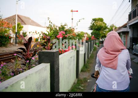 Rear view young asian muslim woman cycling in the street Stock Photo