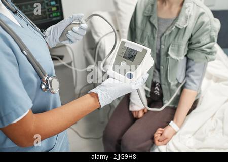 Horizontal high angle view shot of unrecognizable doctor measuring blood pressure of woman in emergency room Stock Photo
