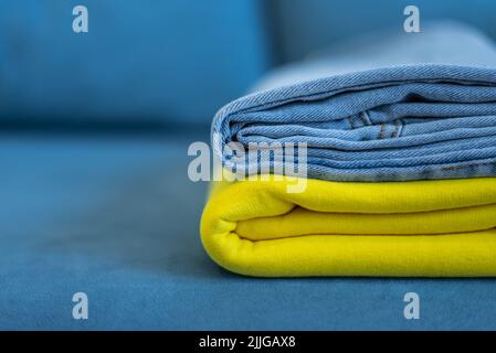 clothes of bright colors are neatly stacked. yellow blue colors of the Ukrainian flag. Stock Photo