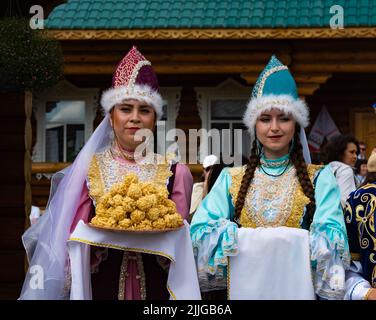 Kazan, Russia. 2022, June 18. Meeting guests according to Tatar customs. Girls in national costumes offer to taste the chak-chak. Traditions of Tatar hospitality Stock Photo