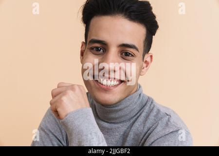 Young middle eastern man smiling and looking at camera isolated over beige background Stock Photo