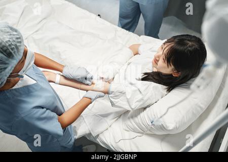 Horizontal high angle view shot of young Asian woman getting intravenous therapy in emergency room Stock Photo