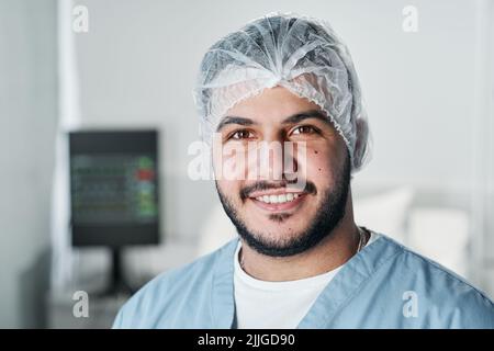 Horizontal close-up portrait of cheerful handsome Middle Eastern doctor with beard on face smiling at camera Stock Photo