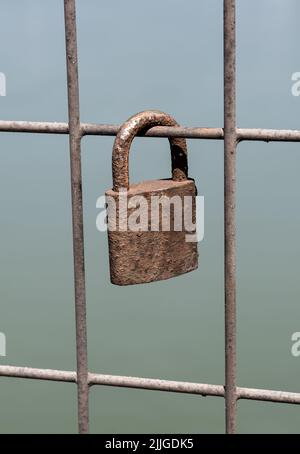 Old Rusty Padlock Fixed On A Wire Fence Symbolizes Eternal Love Stock Photo