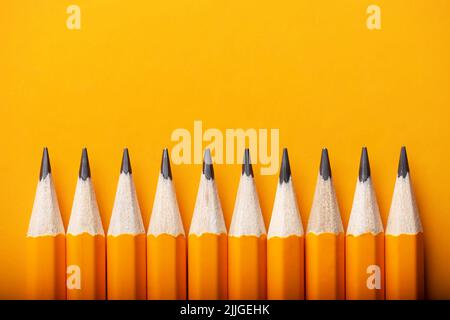 Abstract background of yellow pencils lying in a row. Yellow and orange colour concept Stock Photo