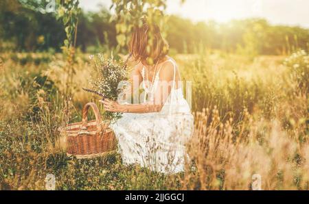 Woman collects beautiful spring flowers in a summer day. Stock Photo