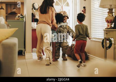 Joyful military homecoming. Happy soldier reuniting with his wife and children after serving in the army. Cheerful serviceman embracing his family aft Stock Photo