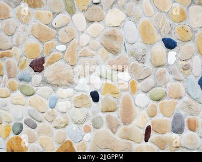 Masonry on the wall of multicolored pebbles. Not seamless texture. Background image. Stock Photo