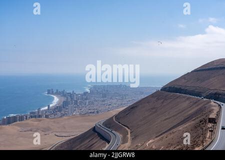 Paragliders flying over Cerro Dragon after launching from Alto Hospico to land on the beach at Iquique below.  Chile. Stock Photo