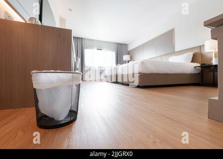 A container trash in the room with plastic inside it in hotel and resort bedroom with wooden floor and furniture background. Stock Photo