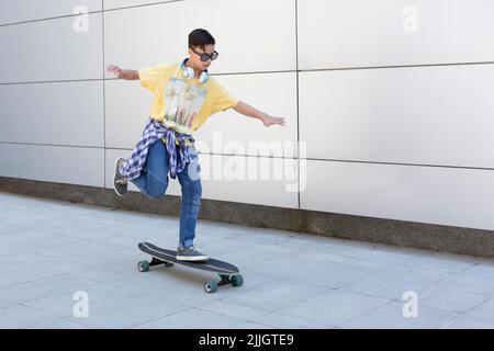 Caucasian teenage boy riding long skateboard on street. Urban lifestyle. Space for text. Stock Photo