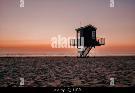 colorful sunset on the beach, mud flat, lifeguard tower on the beach Stock Photo